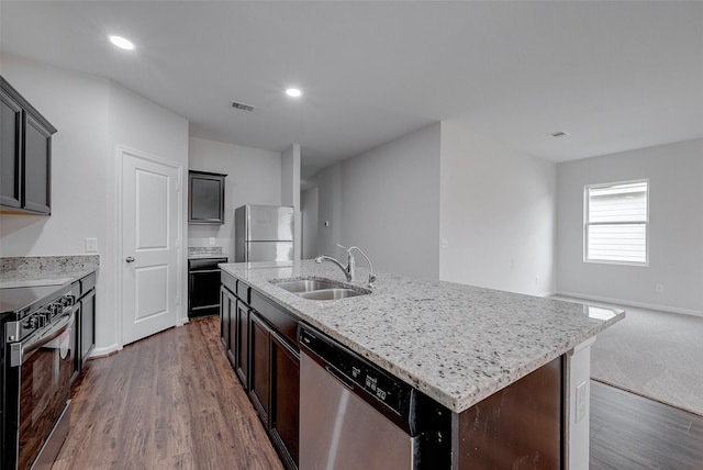 kitchen with dark wood-type flooring, appliances with stainless steel finishes, sink, and a kitchen island with sink