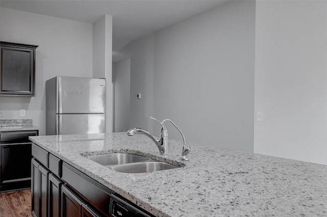 kitchen with sink, stainless steel fridge, dark hardwood / wood-style flooring, light stone countertops, and dark brown cabinets