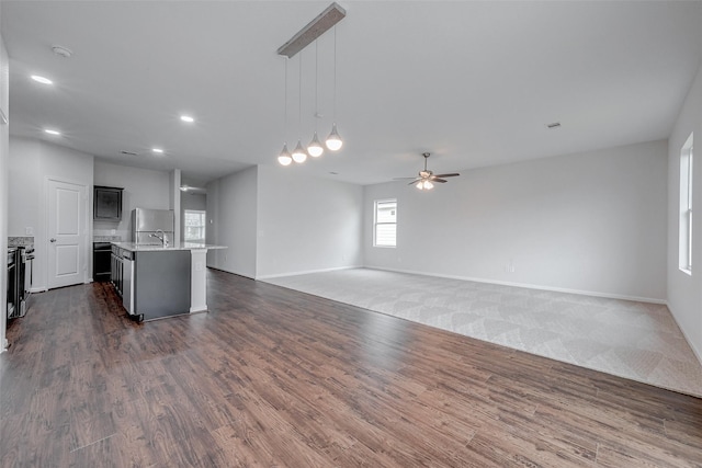 kitchen with decorative light fixtures, refrigerator, a center island with sink, dark hardwood / wood-style floors, and ceiling fan