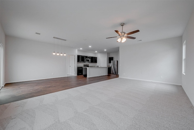 unfurnished living room with dark colored carpet and ceiling fan