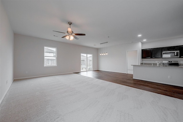 unfurnished living room featuring carpet floors and ceiling fan