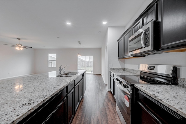 kitchen featuring sink, light stone counters, decorative light fixtures, appliances with stainless steel finishes, and dark hardwood / wood-style flooring