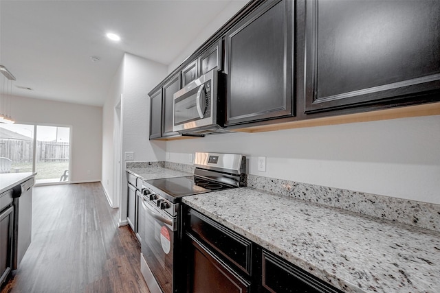 kitchen with light stone countertops, appliances with stainless steel finishes, and dark wood-type flooring