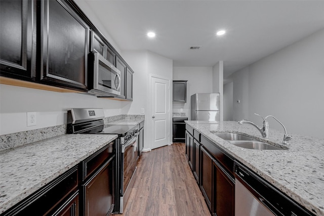 kitchen featuring appliances with stainless steel finishes, dark hardwood / wood-style flooring, light stone countertops, and sink