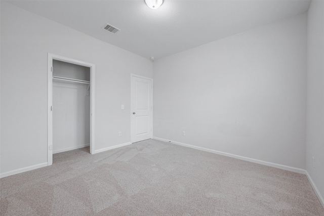 unfurnished bedroom with light carpet and a closet