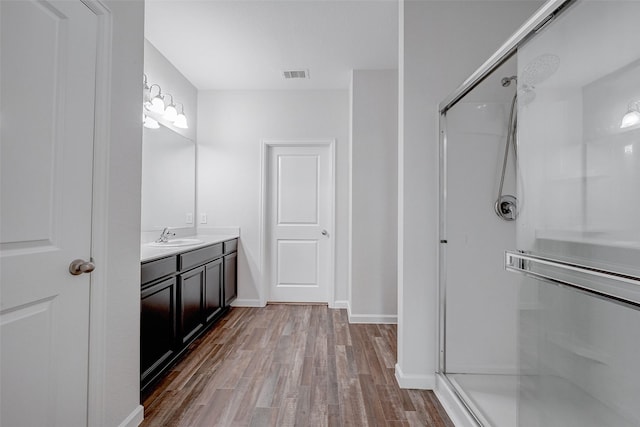 bathroom with a shower with door, wood-type flooring, and vanity