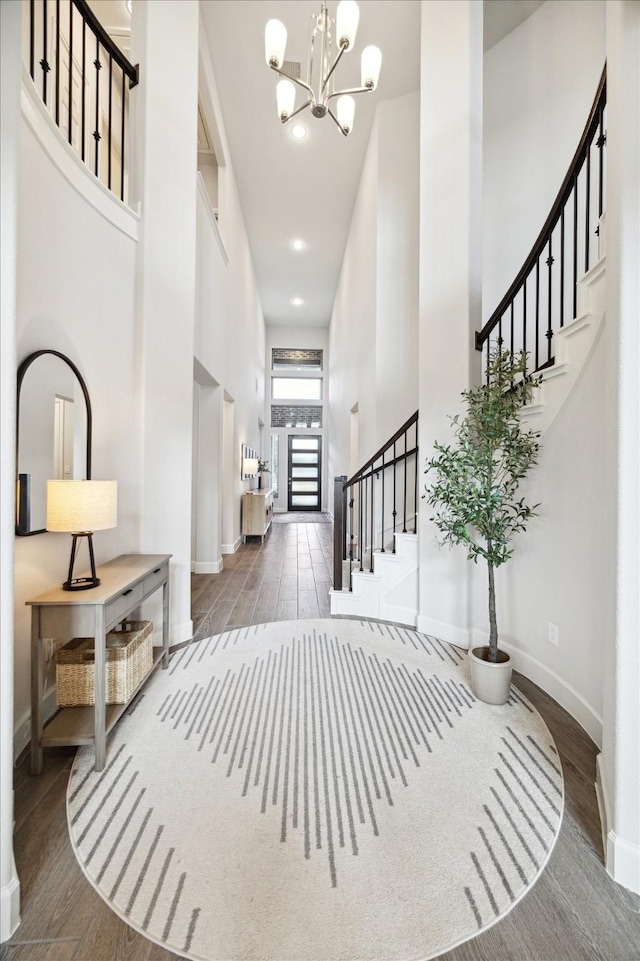 foyer featuring dark wood-type flooring, a towering ceiling, and an inviting chandelier