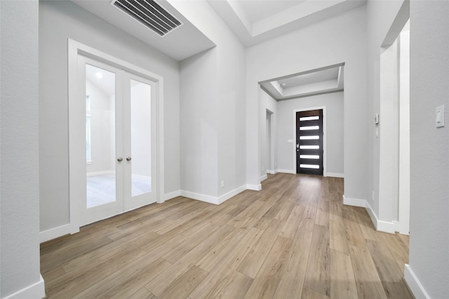 entrance foyer with light hardwood / wood-style flooring, french doors, and a raised ceiling