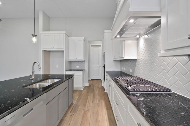 kitchen featuring sink, dark stone countertops, stainless steel appliances, ventilation hood, and white cabinets