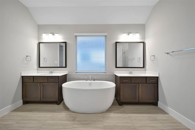 bathroom featuring vanity, a bathing tub, and vaulted ceiling