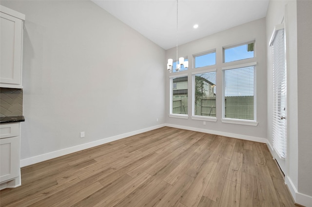 unfurnished dining area featuring an inviting chandelier and light hardwood / wood-style floors