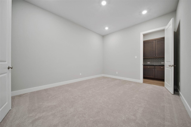 unfurnished bedroom featuring light colored carpet and ensuite bathroom