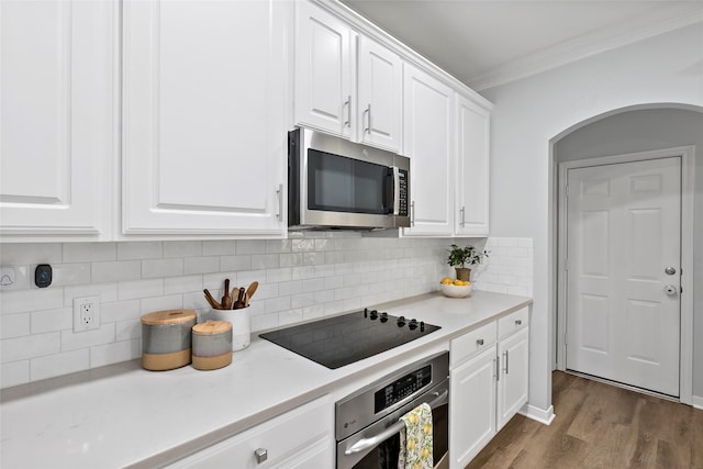 kitchen featuring appliances with stainless steel finishes, white cabinets, backsplash, crown molding, and dark wood-type flooring