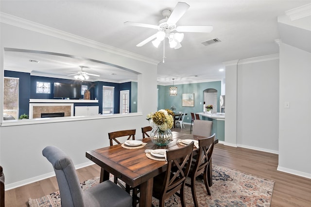 dining area with wood-type flooring, ornamental molding, and ceiling fan