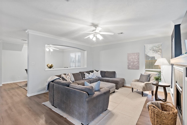 living room with hardwood / wood-style floors, crown molding, and ceiling fan