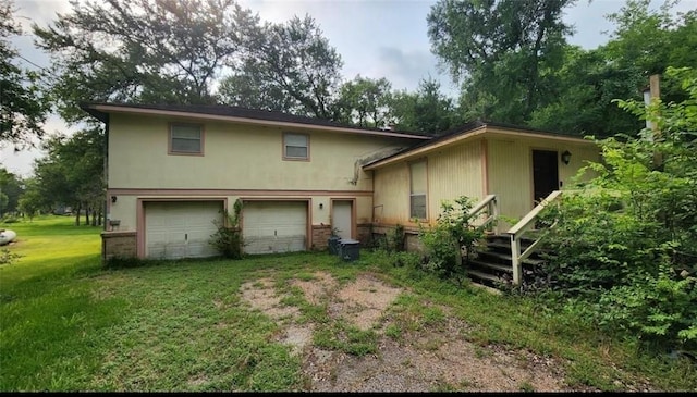 rear view of property featuring brick siding, driveway, an attached garage, and a yard