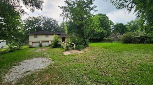 view of yard featuring an attached garage and driveway