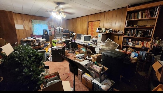 office with a ceiling fan, light colored carpet, and wooden walls