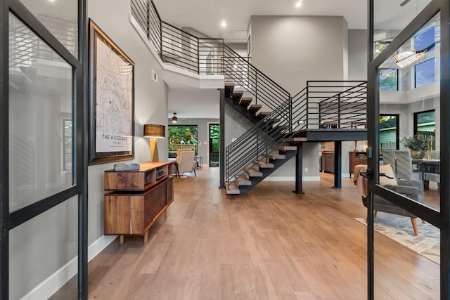 stairway featuring hardwood / wood-style flooring, a towering ceiling, and ceiling fan