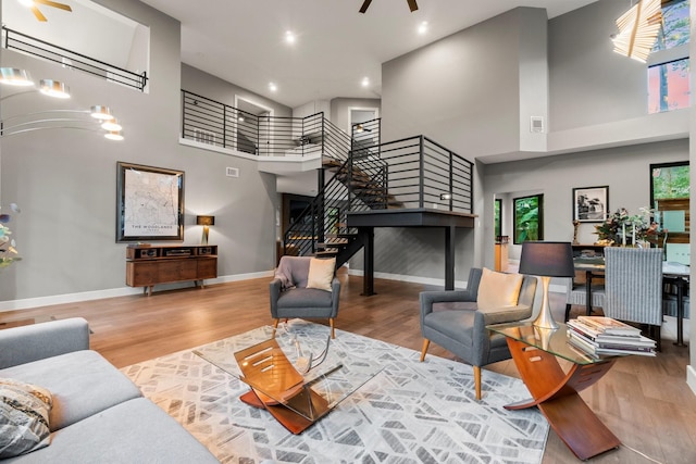 living room with ceiling fan, hardwood / wood-style floors, and a towering ceiling