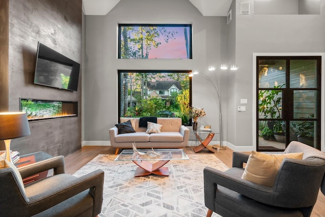 living room with a fireplace, hardwood / wood-style floors, and a high ceiling