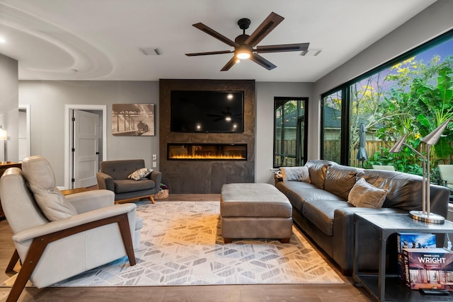 living room featuring hardwood / wood-style floors, a fireplace, and ceiling fan