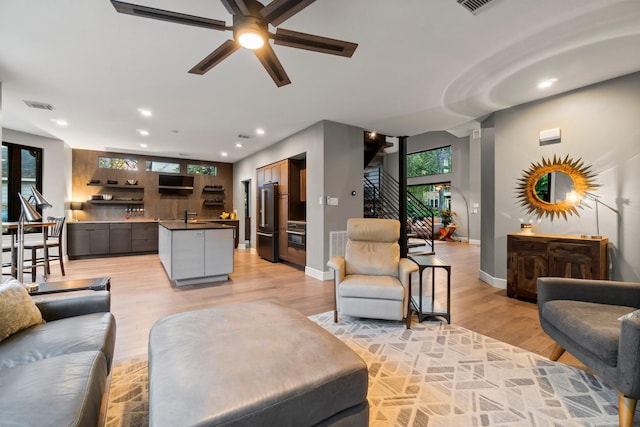 living room with ceiling fan, plenty of natural light, sink, and light wood-type flooring