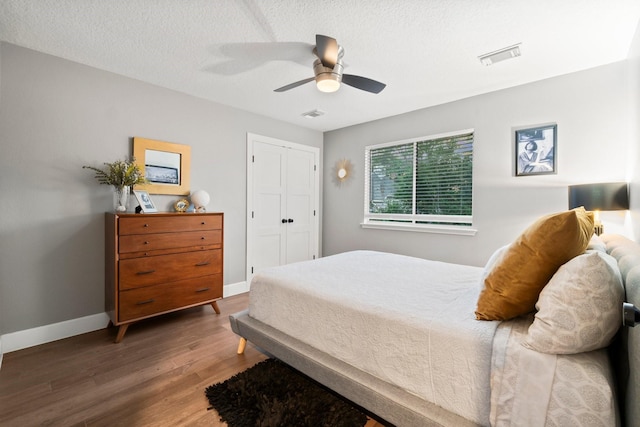 bedroom with ceiling fan, dark hardwood / wood-style floors, and a textured ceiling