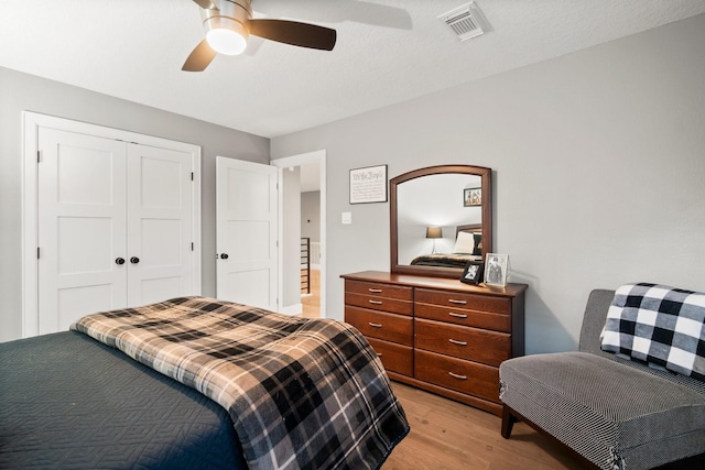 bedroom with ceiling fan, light hardwood / wood-style floors, and a closet