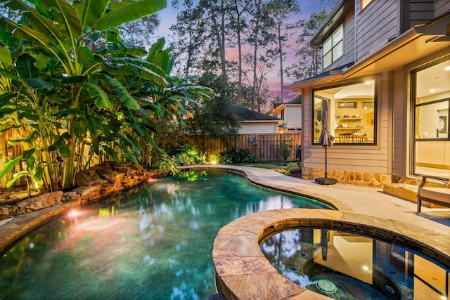 pool at dusk with a patio area