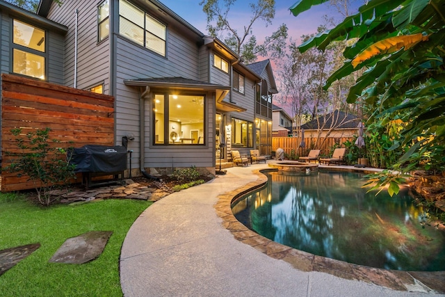 pool at dusk with grilling area and a patio area