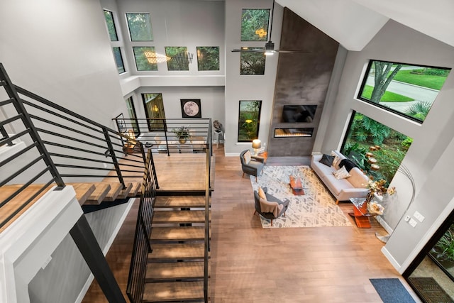 living room featuring a towering ceiling, a fireplace, and hardwood / wood-style floors