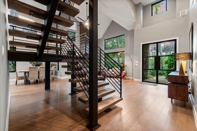 stairs featuring hardwood / wood-style floors and a high ceiling