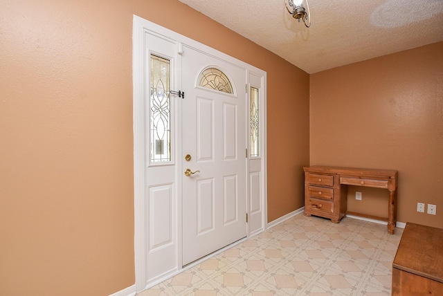 foyer entrance with light floors, baseboards, and a textured ceiling