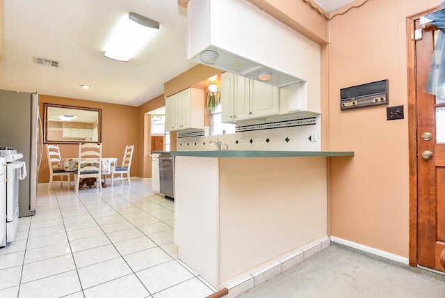 kitchen featuring visible vents, white range, a sink, a peninsula, and light tile patterned floors