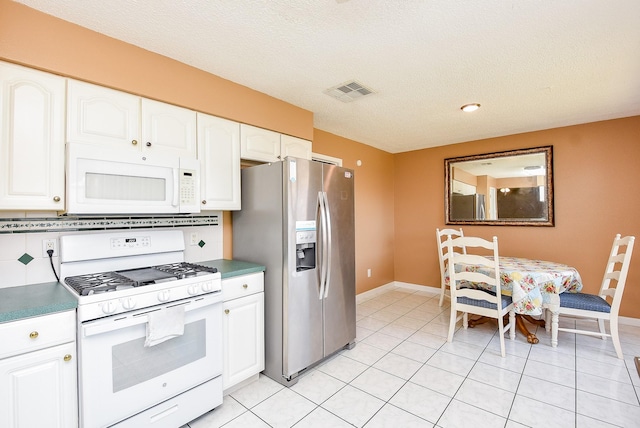 kitchen with light tile patterned flooring, visible vents, white appliances, and white cabinetry