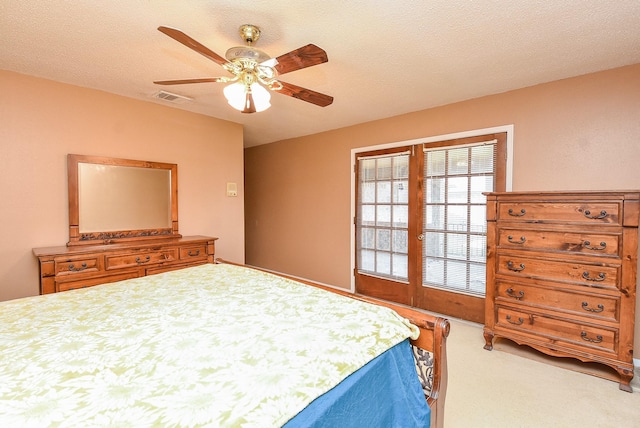 carpeted bedroom with visible vents, a textured ceiling, and ceiling fan