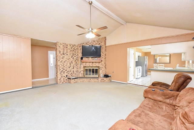 living room with beamed ceiling, light carpet, a fireplace, a textured ceiling, and a ceiling fan