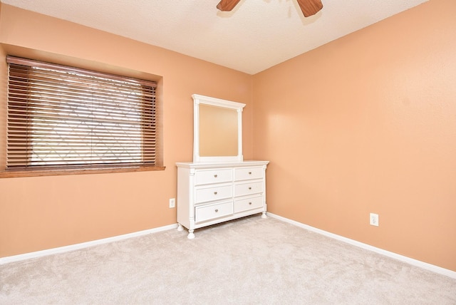 unfurnished bedroom featuring baseboards, light colored carpet, a ceiling fan, and a textured ceiling