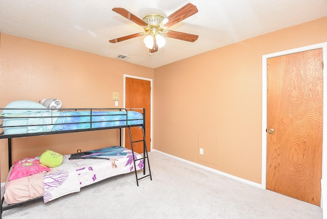 carpeted bedroom featuring visible vents, baseboards, a textured ceiling, and ceiling fan