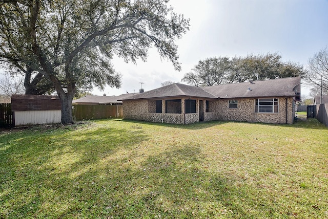 rear view of property with brick siding, a storage shed, a yard, an outdoor structure, and a fenced backyard