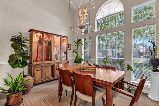 dining room featuring a high ceiling, a chandelier, and light wood-type flooring