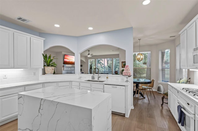 kitchen with a kitchen island, sink, white cabinets, kitchen peninsula, and white appliances