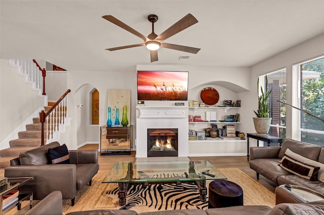 living room with a tiled fireplace, hardwood / wood-style flooring, and ceiling fan