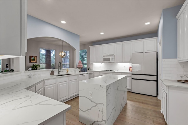 kitchen with white cabinetry, light stone countertops, sink, and white appliances