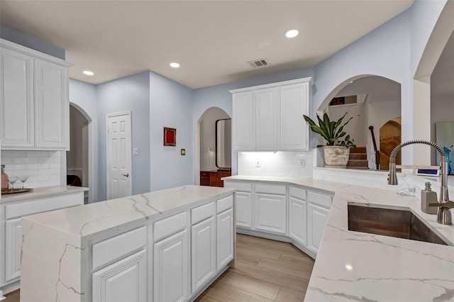 kitchen with sink, white cabinets, and light stone counters