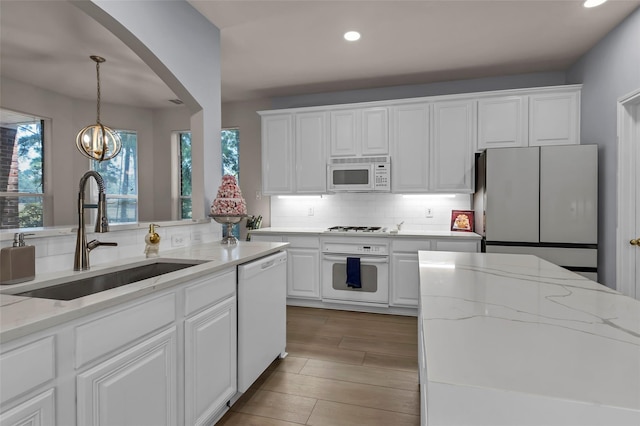 kitchen featuring sink, white appliances, light stone countertops, and white cabinets