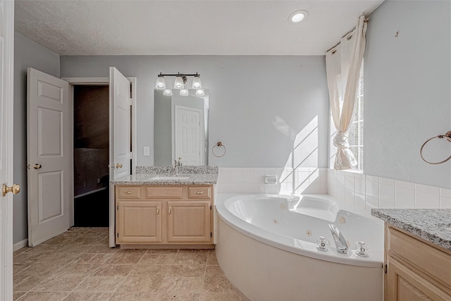 bathroom featuring a tub to relax in, vanity, and a textured ceiling