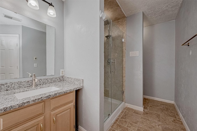 bathroom featuring vanity, a shower with shower door, and a textured ceiling