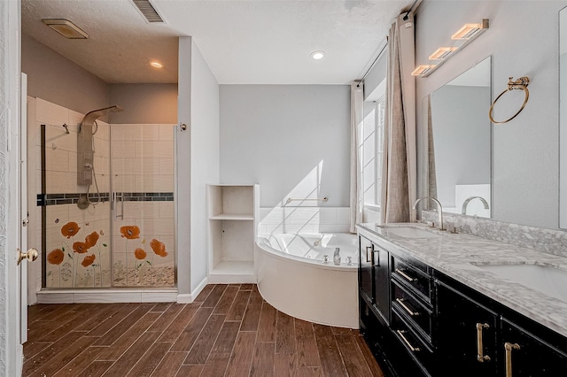 bathroom featuring plus walk in shower, vanity, and a textured ceiling